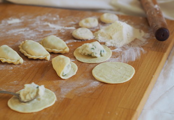 On the kitchen cutting board, ready-made dumplings with ingredients for making dough and various kitchen utensils.