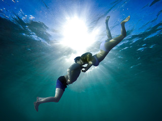 Young guy and girl kiss underwater - romantic scene.