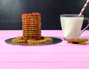 Cookies with jam and milk in a glass for breakfast. Confectionery for the holiday. Sweet dessert made from flour. Dairy product in a glass bowl.