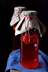 Homemade strawberry liquor in the glass bottles is infusing against the black background