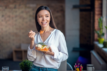 Joyful young woman eating a vegetable salad