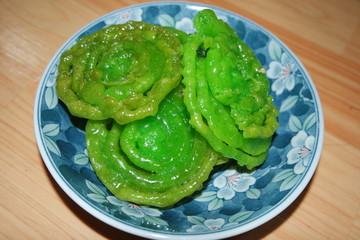 Crispy sweet Asian dessert green Jalebi cooked and served in ceramic plate.