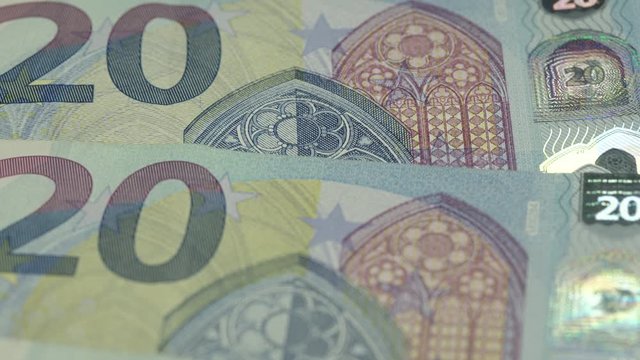 euro banknotes with traditional green images and numbers rotate under white electric light extreme close view