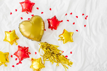 Balloon of heart and stars shaped with confetti on white bed. Love concept. Holiday celebration. Valentine's Day or birthday/bachelorette party decoration. Metallic balloon