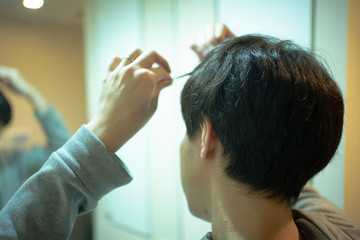 洗面所で髪を整える男性