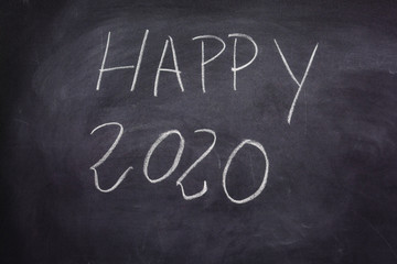 Obraz premium Phrase wishing a happy new year 2020 written on a blackboard