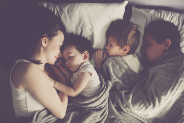 family with two children sleeping in bed,top view