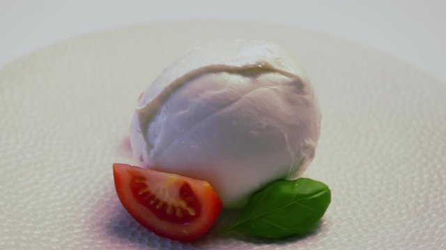 Soft white italian mozzarella cheese rotating on white plate