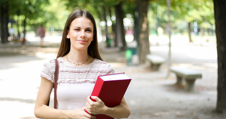 Fototapeta premium Smiling student outdoor holding a book
