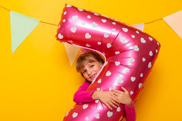 Birthday girl holding giant balloon shaped as number seven