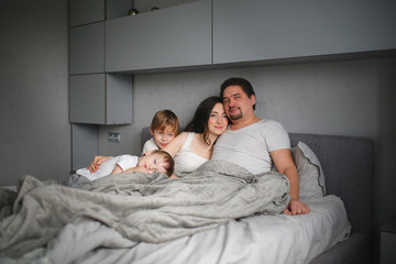 Obraz na płótnie Canvas Hispanic family with two children, morning on bed