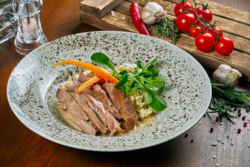 Tasty, fresh Salad with duck breast, spinach, quinoa, quail eggs and cherry tomatoes in a white bowl on a wooden background. Healthy Fitness Nutrition. Close up food
