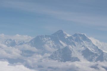 A beautiful photo of a mountain with glacier and snow on it from a height above the clouds