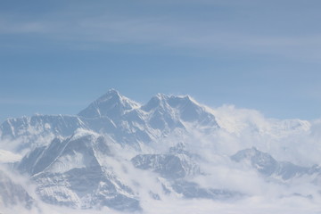A beautiful photo of a mountain with glacier and snow on it from a height above the clouds