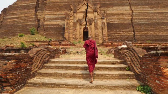 Asian Monk Walking In Front Of Burmese Ancient Buddhist Temple. 4K Slow Motion Footage. Mandalay, Myanmar.