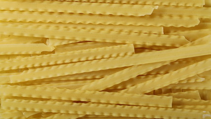 Uncooked Italian pasta mafaldine background and texture