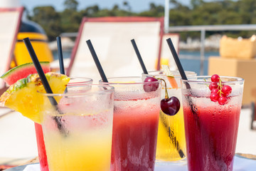 Closeup shot of orange and red drinks with black straws