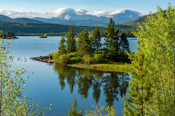 Dillon reservoir at sunrise, reflection of trees in water.