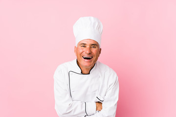 Middle aged cook man isolated laughing and having fun.