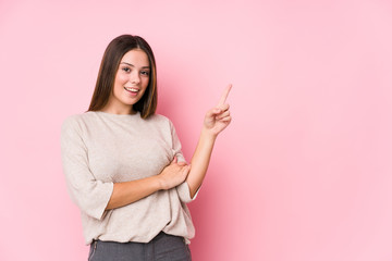 Young caucasian woman posing isolated smiling cheerfully pointing with forefinger away.