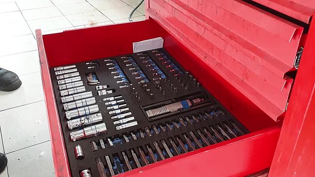 close-up of hands of mechanic folding working tools in red metal box