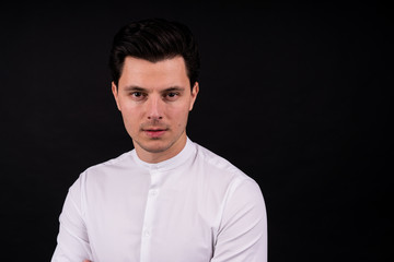 Obraz premium serious guy looking at the camera. Dressed in a white shirt, black background