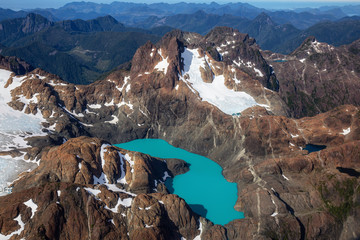 Aerial View of the Rugged Mountain with colorful glacier lake during a sunny summer morning. Taken in Woss Lake Provincial Park, Vancouver Island, BC, Canada.