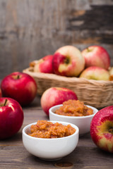 Fresh applesauce in bowls and red apples on a wooden table. Baby food