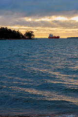 Obraz premium Waving water of stormy sea on a sunset with a ship on a background. Copy space.