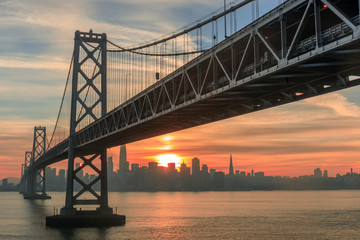 Sun setting over the western span of the Bay Bridge and San Francisco waterfront. Shot from Yerba Buena Island, San Francisco, California, USA.