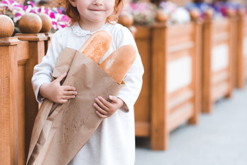 Little baby girl 2-3 year old holding fresh bread outdoors closeup. Childhood. Good morning.