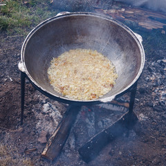 A series of the process of cooking pilaf in a cauldron on the street. handmade oriental cuisine. frying onions.