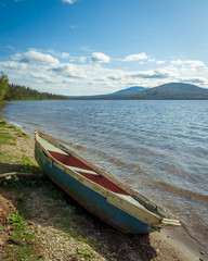 old wooden boat on the shore of a mountain lake. ecological tourism in the fresh air