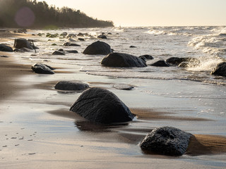 backlit landscape with stony sea shore