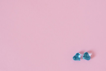 Glass hearts on a beautiful pink pastel background. Two blue hearts