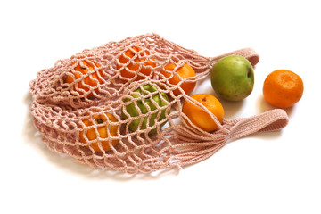 Peach Coloured Hand-Made Crochet Eco-Friendly String Shopping Bag with Green Apples and Tangerines  on White Background. Concept of Ecology, Environmental Protection & Zero Waste