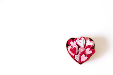 Cardboard box in the form of a heart with different hearts inside on a light background