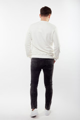 Fototapeta na wymiar Young european man in white sweater and black pants posing on white background. Isolated.