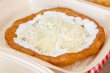 Langos - traditional hungarian food a deep fried flat bread topped with cheese and sour cream, jam or chocolate, a popular fast food and street food snack.