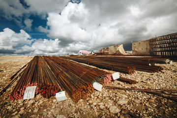 Long metal fittings stacked on the ground before construction