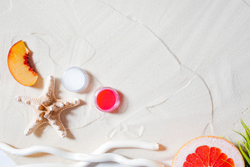 Wonderful beach. Lipstick, lip gloss, lip balm lie on the sand, surrounded by juicy fruits,...