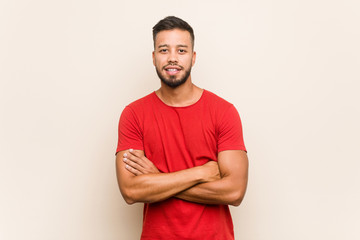 Young south-asian man who feels confident, crossing arms with determination.