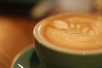 cup of coffee with cream on wooden background