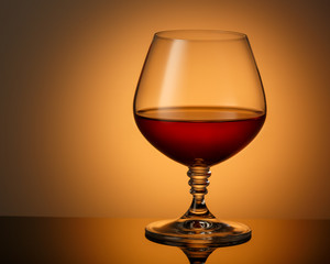 A glass of cognac on a dark surface with a reflection. Space for text