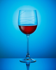 A glass of red wine on a blue background.