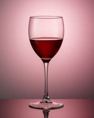 A glass of red wine on a dark surface with a reflection