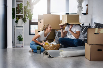 Happy young couple unpacking or packing boxes and moving into a new home 