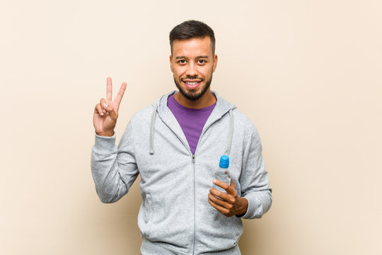 Young mixed race asian man holding a water bottle showing number two with fingers.