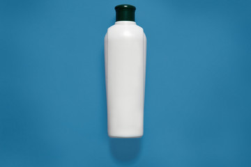 Cosmetic package, mockup, white empty plastic bottle with black cap, containers, clean plastic container, copy space for promotional text or advertisment, isolated over blue studio background.