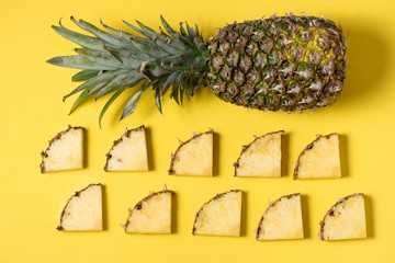 fresh and juicy pineapple pieces on a yellow homogeneous surface. Fruit ready to eat